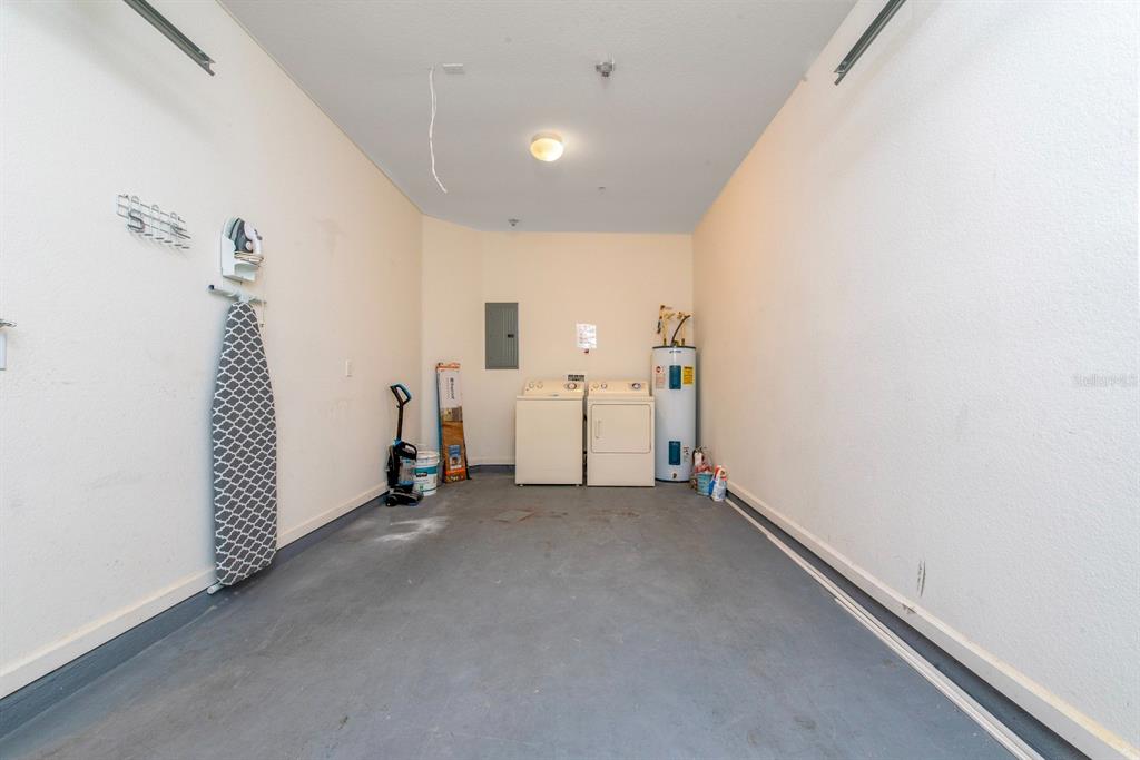 A laundry room with a washer, dryer, water heater, and an ironing board on the wall — 4816 TIDECREST AVENUE UNIT 175, ORLANDO, FL