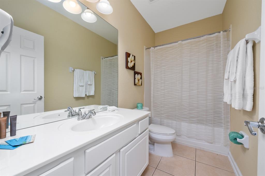 A bathroom features a white vanity, a toilet, and a shower with a textured curtain — 4816 TIDECREST AVENUE UNIT 175, ORLANDO, FL