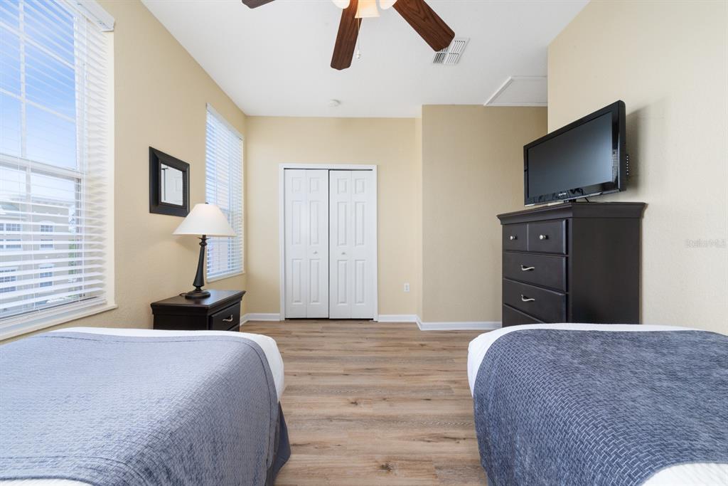 A bedroom features two beds, a dresser with a television, and light-colored wood flooring — 4816 TIDECREST AVENUE UNIT 175, ORLANDO, FL