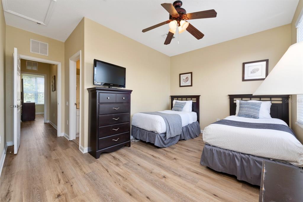 A bedroom with two twin beds, a dark wood dresser with a television, and wood flooring — 4816 TIDECREST AVENUE UNIT 175, ORLANDO, FL