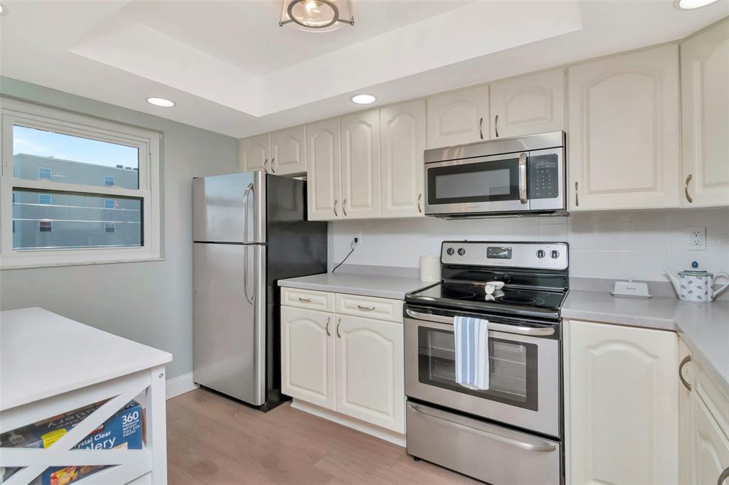 A kitchen features light-colored cabinets, stainless steel appliances, and light wood-look flooring — 17580 GULF BOULEVARD UNIT 403, REDINGTON SHORES, FL