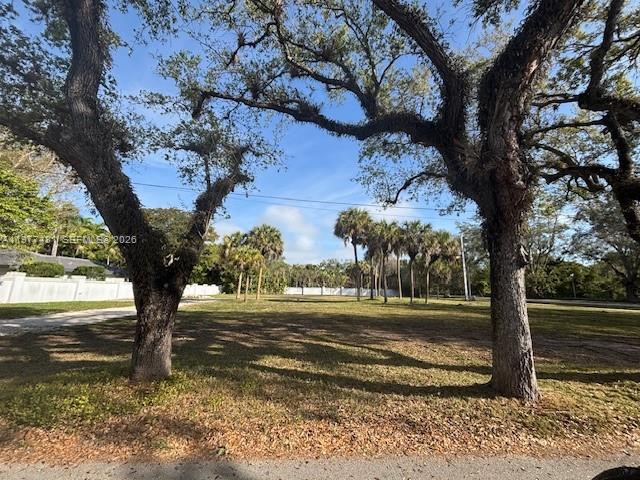 A vacant, grassy lot framed by two large oak trees under a clear blue sky — 9506 SW 57th Ave, Pinecrest FL 33156, PINECREST, FL