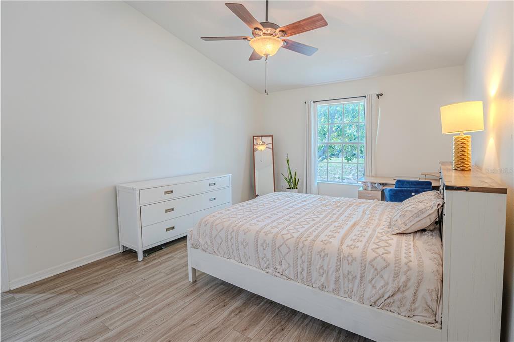 A bedroom features a white bed, a white dresser, a desk, and wood-look flooring — 1236 N FAIRWAY DRIVE, APOPKA, FL