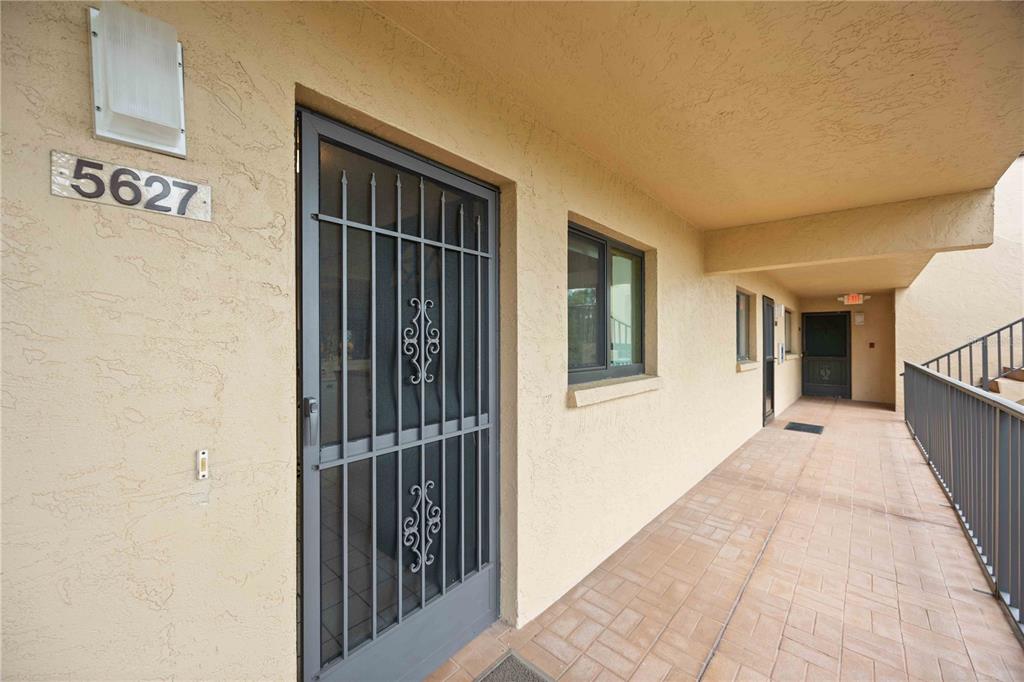 An exterior view of a building entrance with a security screen door and walkway — 5627 ASHTON WAY UNIT 5627, SARASOTA, FL