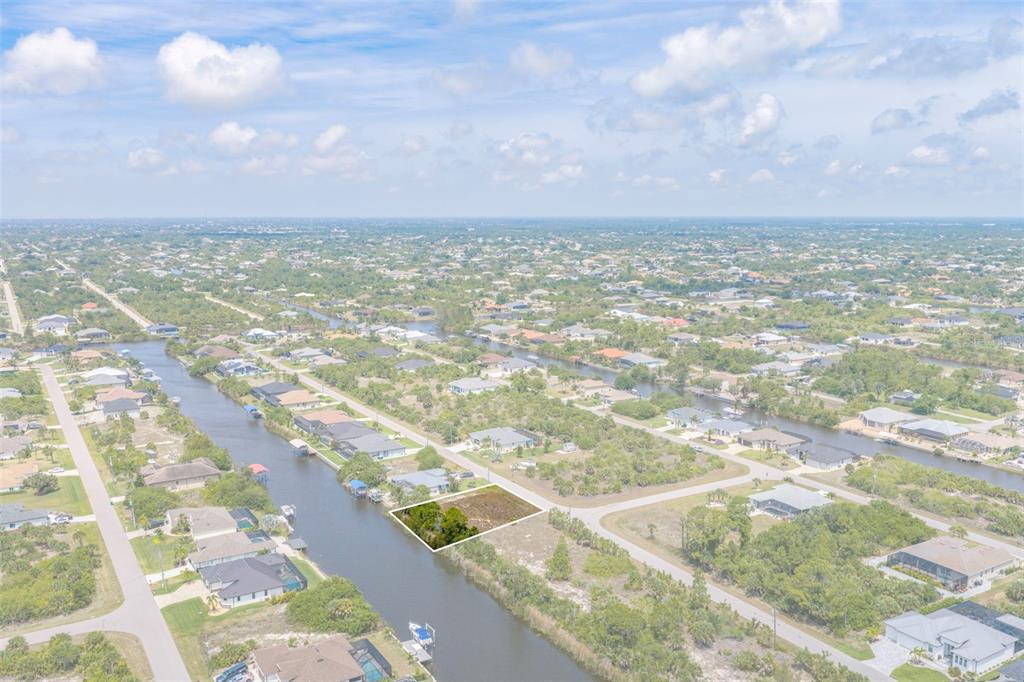 An aerial view shows a vacant waterfront lot highlighted in a residential neighborhood — 15424 HENNIPEN CIRCLE, PORT CHARLOTTE, FL