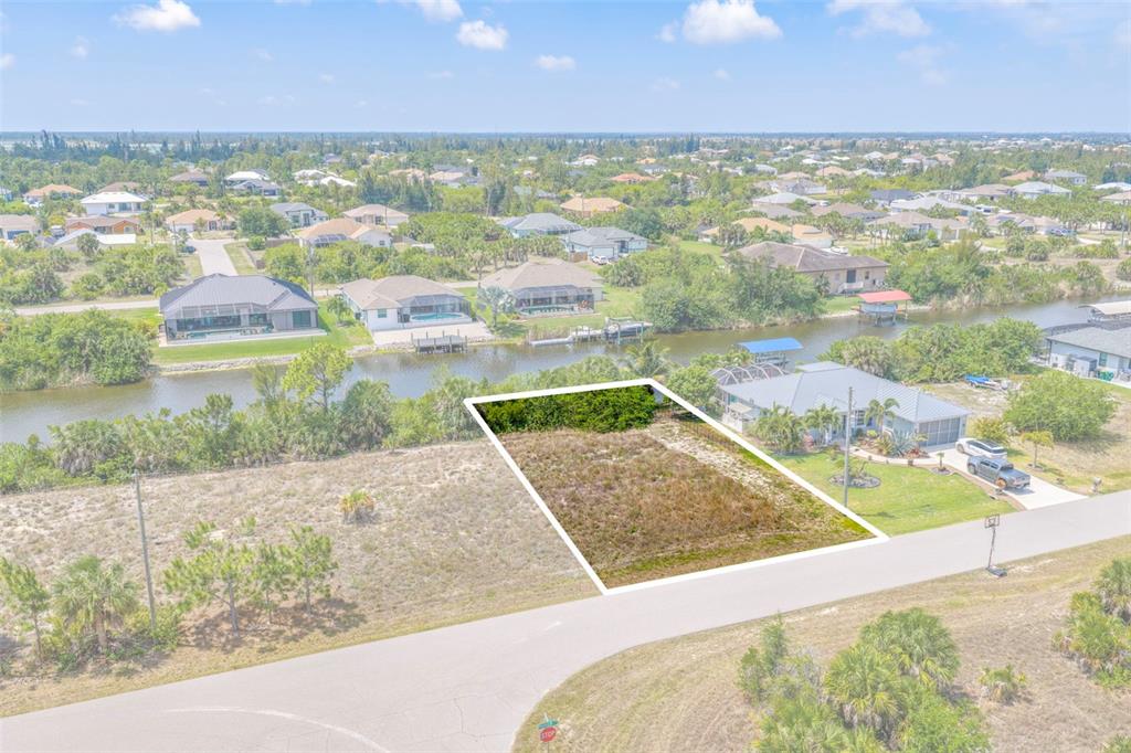 An aerial view shows a vacant, rectangular residential lot bordering a canal — 15424 HENNIPEN CIRCLE, PORT CHARLOTTE, FL