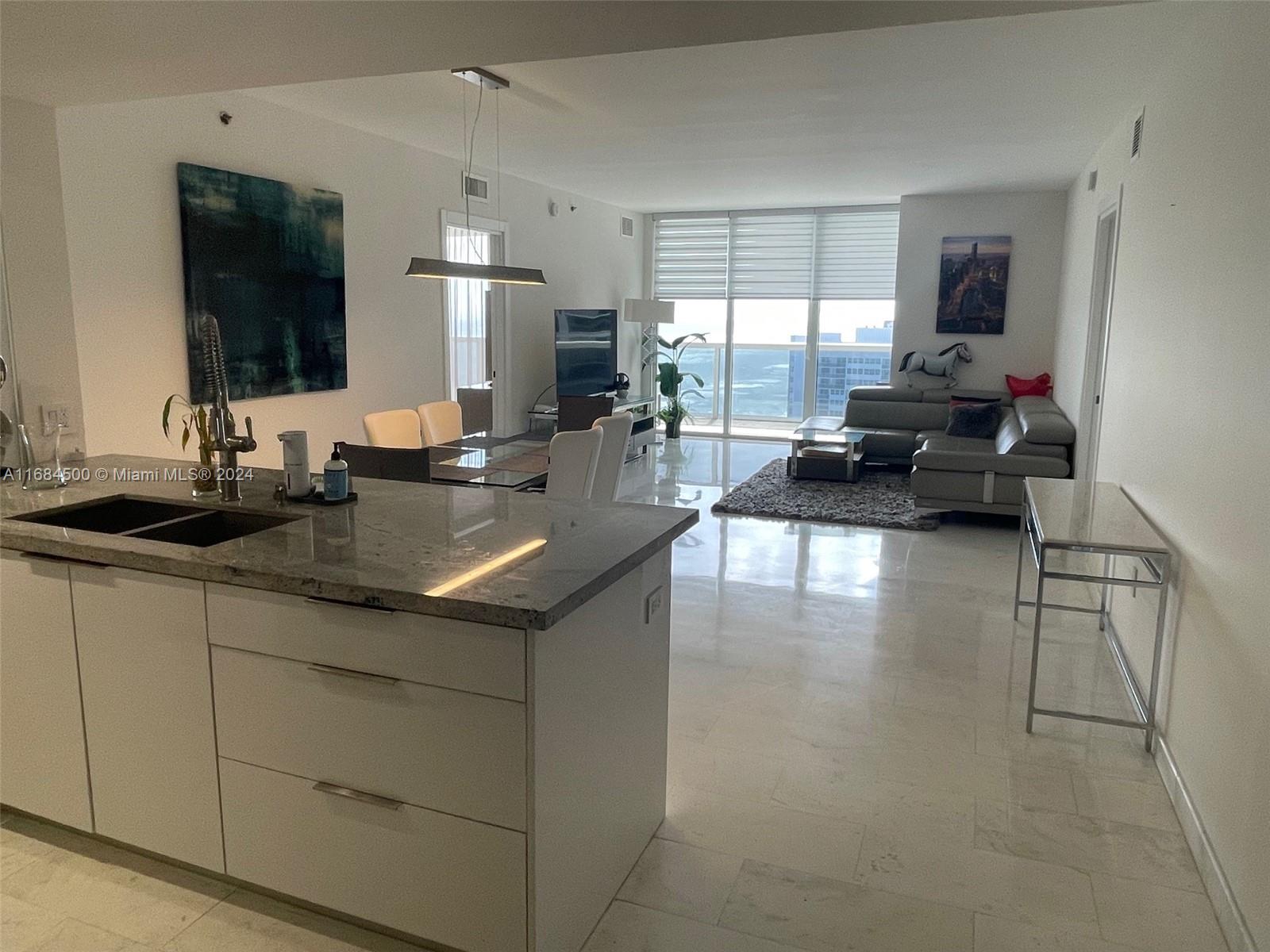 A modern open-concept living area features a kitchen island, dining space, and floor-to-ceiling windows — 1830 S Ocean Dr # 2604, Hallandale Beach FL 33009, HALLANDALE BEACH, FL