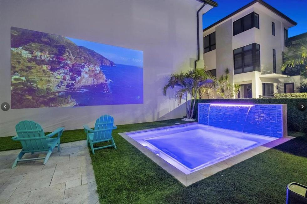 A backyard features a small pool with a waterfall, artificial turf, and a wall-mounted projector screen — 8225 Central Park Boulevard, Doral FL 33166, DORAL, FL