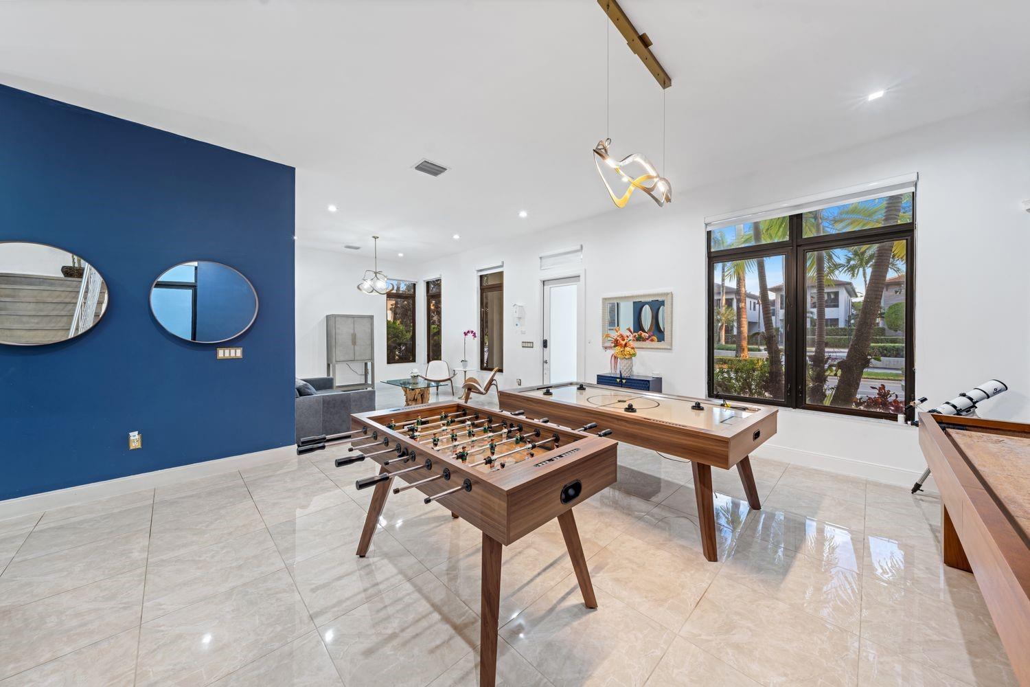 A game room features a foosball table, air hockey table, tile floors, and a blue wall — 8225 Central Park Boulevard, Doral FL 33166, DORAL, FL