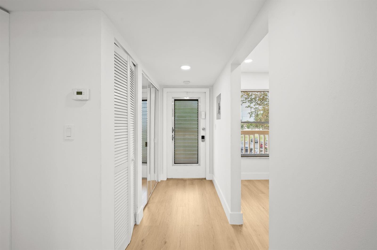 A bright entryway features light wood flooring, white walls, a closet, and a front door — 6000 NW 64th Avenue # 303, Tamarac FL 33319, TAMARAC, FL