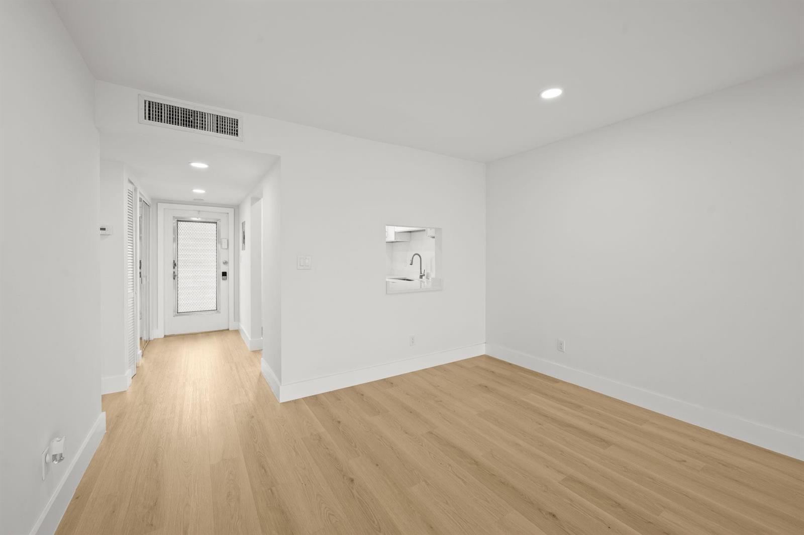 A minimalist room with light wood flooring, white walls, and a small built-in wet bar — 6000 NW 64th Avenue # 303, Tamarac FL 33319, TAMARAC, FL