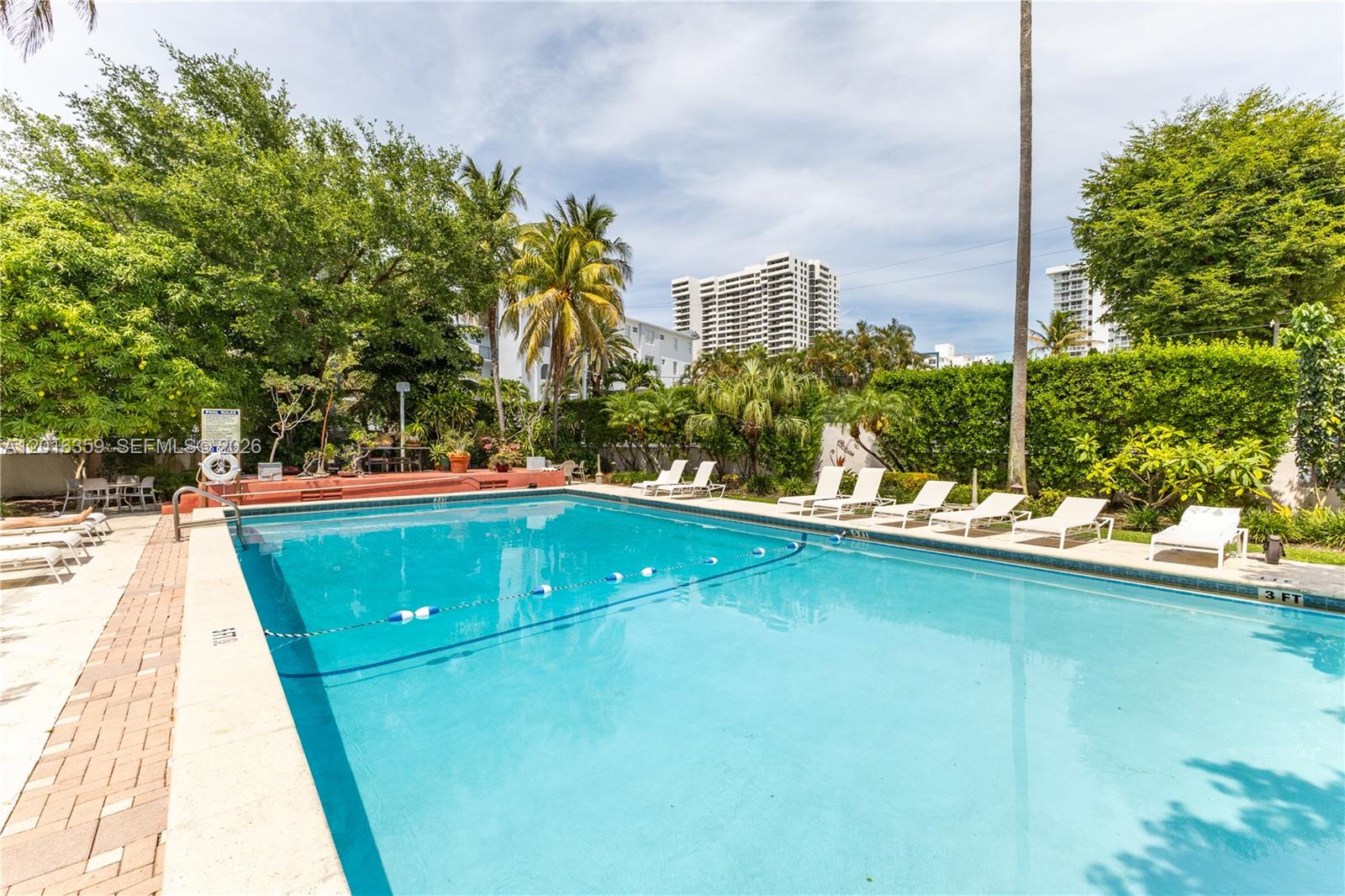 An outdoor swimming pool is surrounded by lounge chairs, palm trees, and a privacy hedge — 255 W 24th St # 432, Miami Beach FL 33140, MIAMI BEACH, FL