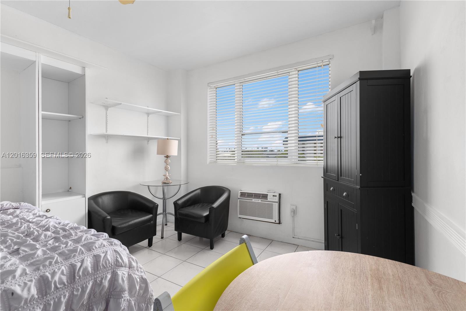 A bedroom features white walls, tiled floors, two black chairs, and a tall black cabinet — 255 W 24th St # 432, Miami Beach FL 33140, MIAMI BEACH, FL