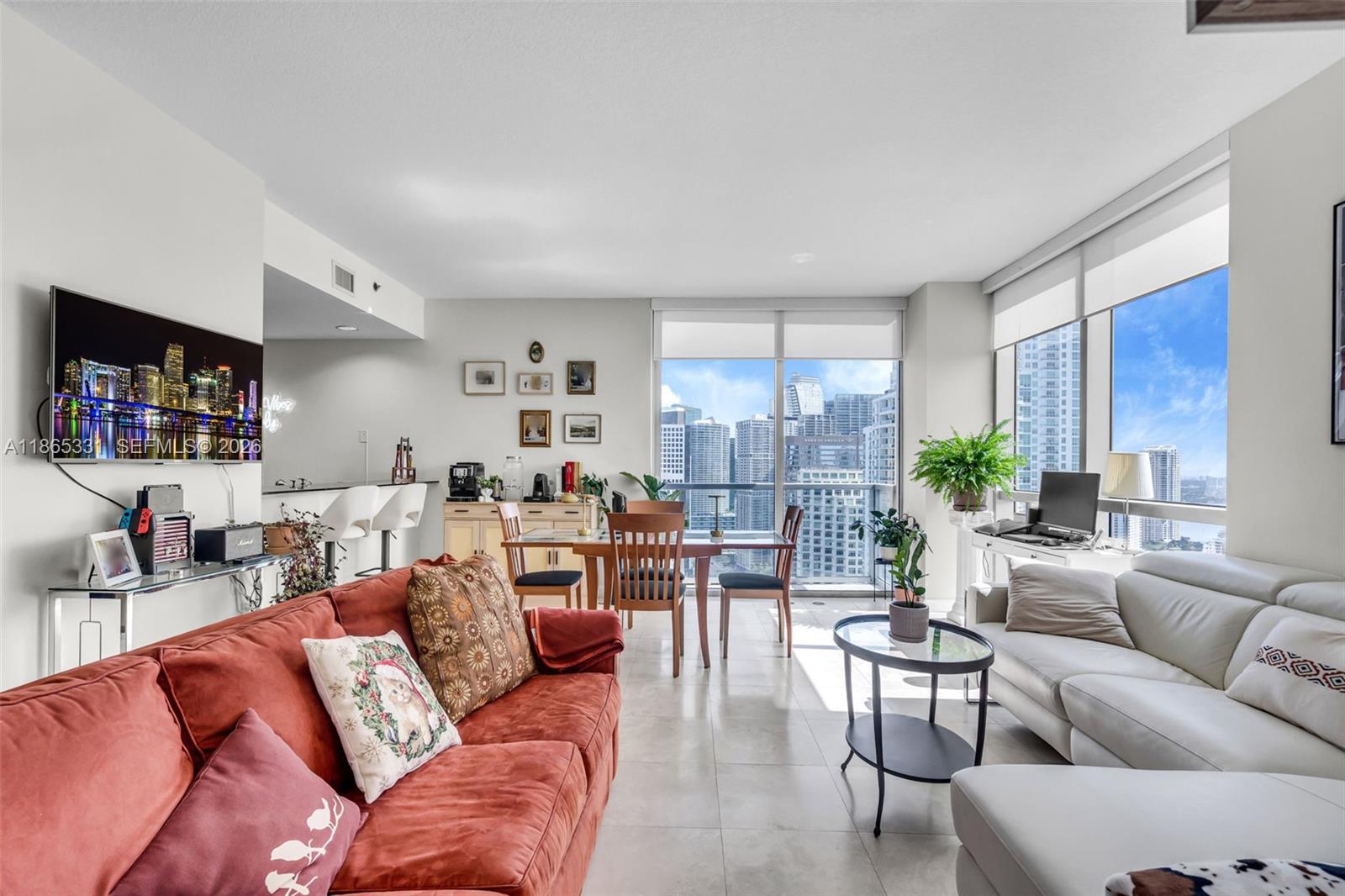 A living and dining area features a red sofa, white sectional, and floor-to-ceiling city views — 1060 Brickell Ave # 3601, Miami FL 33131, MIAMI, FL