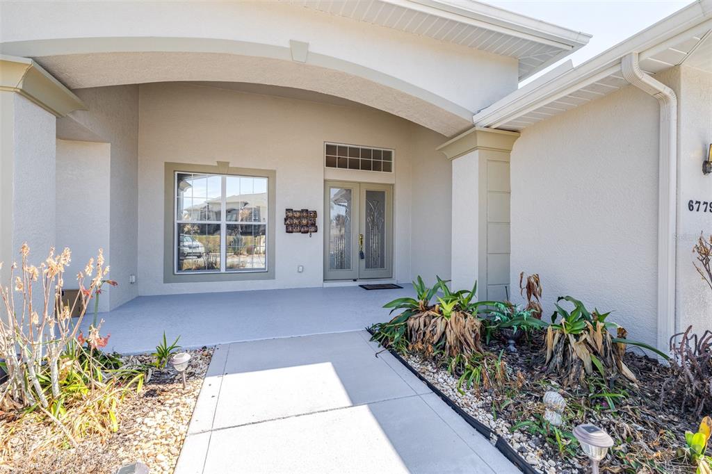 The exterior view shows a covered entryway with a double front door and a window — 6779 HUNTINGTON HILLS BOULEVARD, LAKELAND, FL