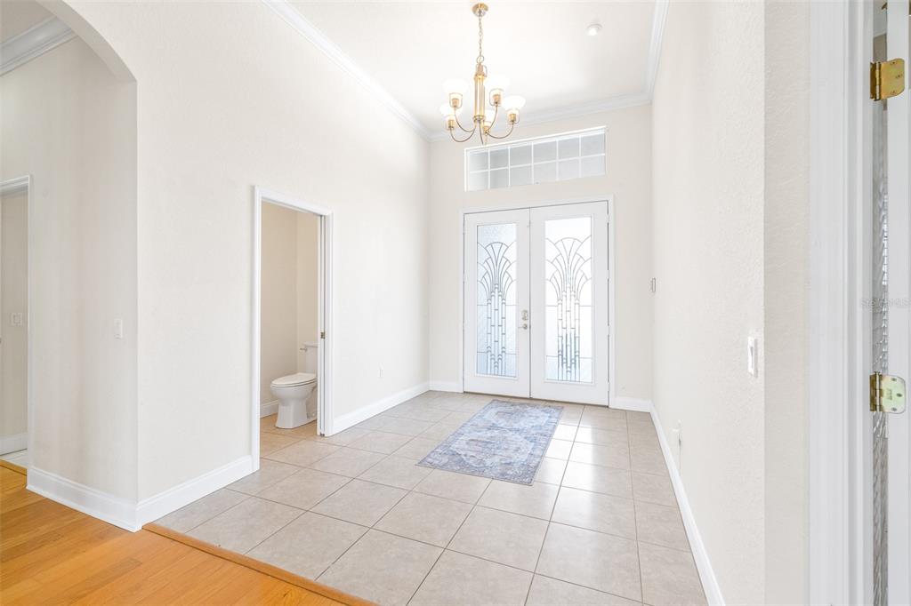 A tiled entryway features a chandelier, double glass-paneled front doors, and an adjacent half bathroom — 6779 HUNTINGTON HILLS BOULEVARD, LAKELAND, FL