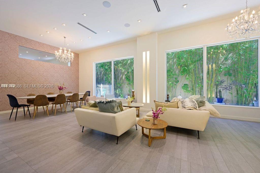 A bright, open-concept living and dining area features tile floors, chandeliers, and floor-to-ceiling windows — 1615 NE 196th St, Miami FL 33179, MIAMI, FL