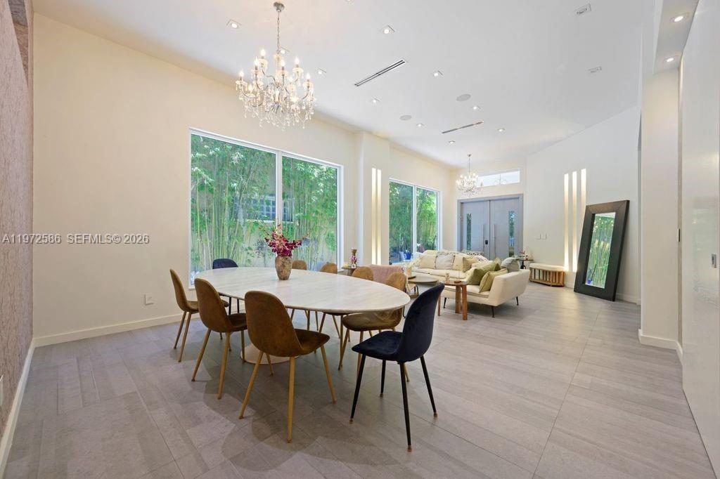 A dining area with an oval table and chandelier opens into a living room space — 1615 NE 196th St, Miami FL 33179, MIAMI, FL