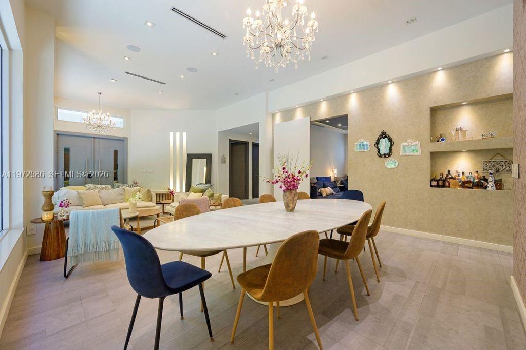 A dining room with an oval table and chandelier opens into a living area — 1615 NE 196th St, Miami FL 33179, MIAMI, FL