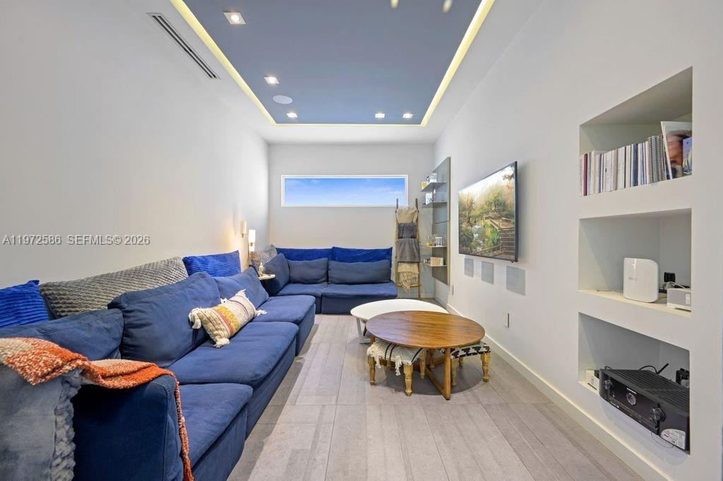 A living room features a blue sectional sofa, a wooden coffee table, and built-in shelving — 1615 NE 196th St, Miami FL 33179, MIAMI, FL