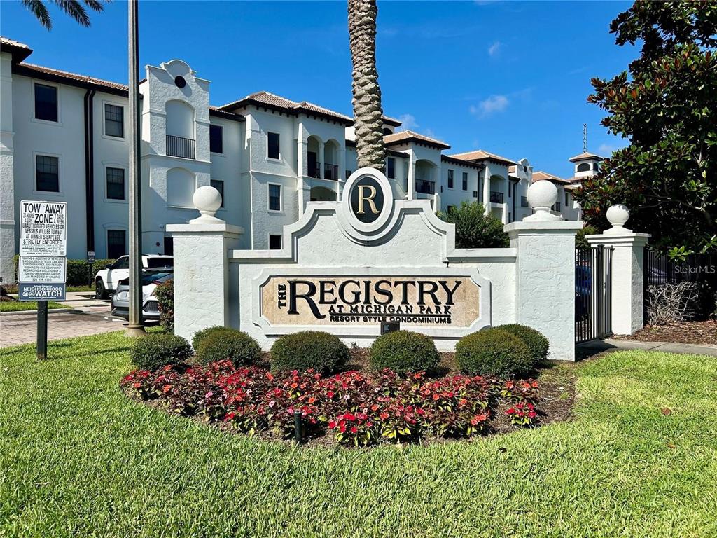 A white stone monument sign for The Registry at Michigan Park stands before apartment buildings — 5550 E MICHIGAN STREET UNIT 2228, ORLANDO, FL