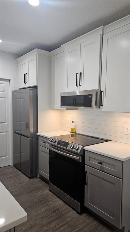 A kitchen features white upper cabinets, gray lower cabinets, stainless steel appliances, and white countertops — 5550 E MICHIGAN STREET UNIT 2228, ORLANDO, FL