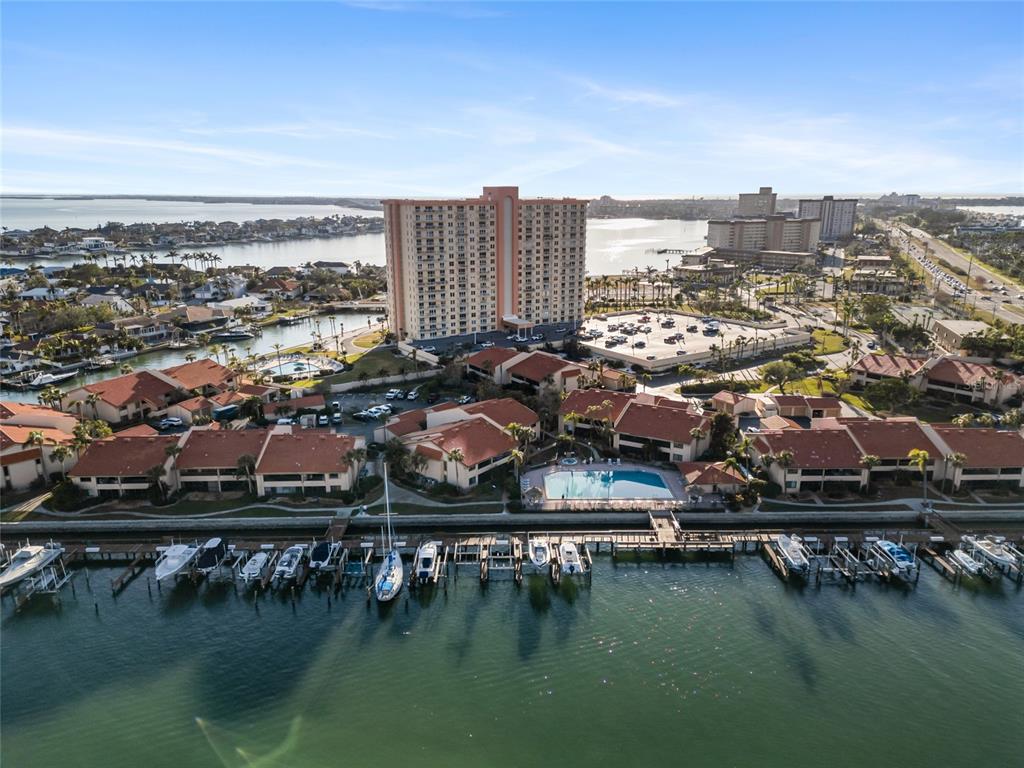 An aerial view shows a waterfront condominium complex with a boat dock and high-rise building — 4900 BRITTANY DRIVE S UNIT 1003, ST PETERSBURG, FL