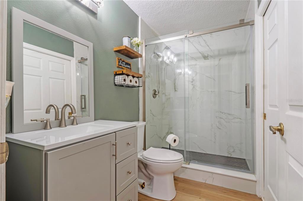 A bathroom features a gray vanity, a walk-in glass shower, and green walls — 425 BLACK IRONWOOD DRIVE, DELAND, FL