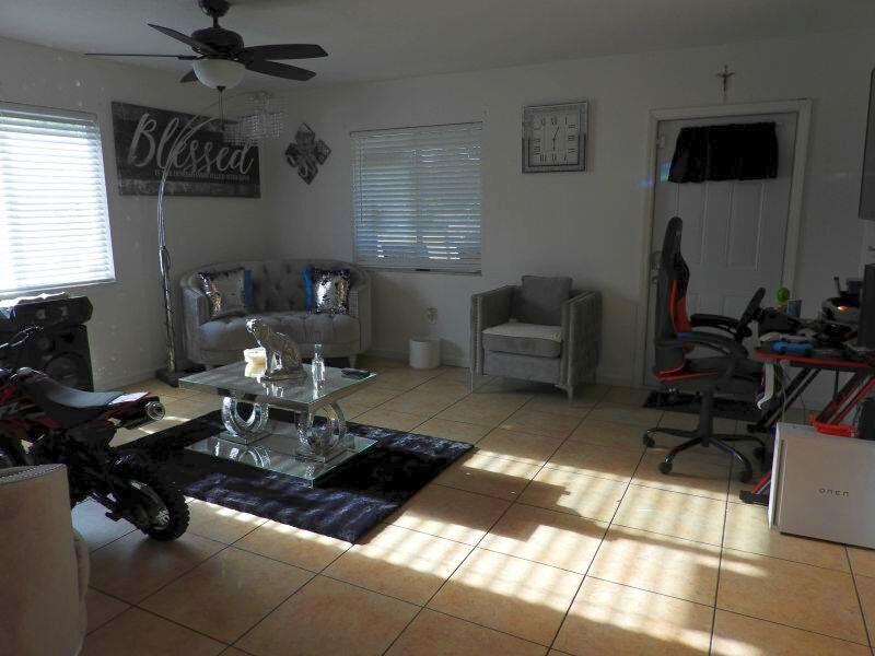 A living room features tile flooring, a coffee table, a sofa, and a gaming chair — 2764 NW 1st Court, Pompano Beach FL 33069, POMPANO BEACH, FL