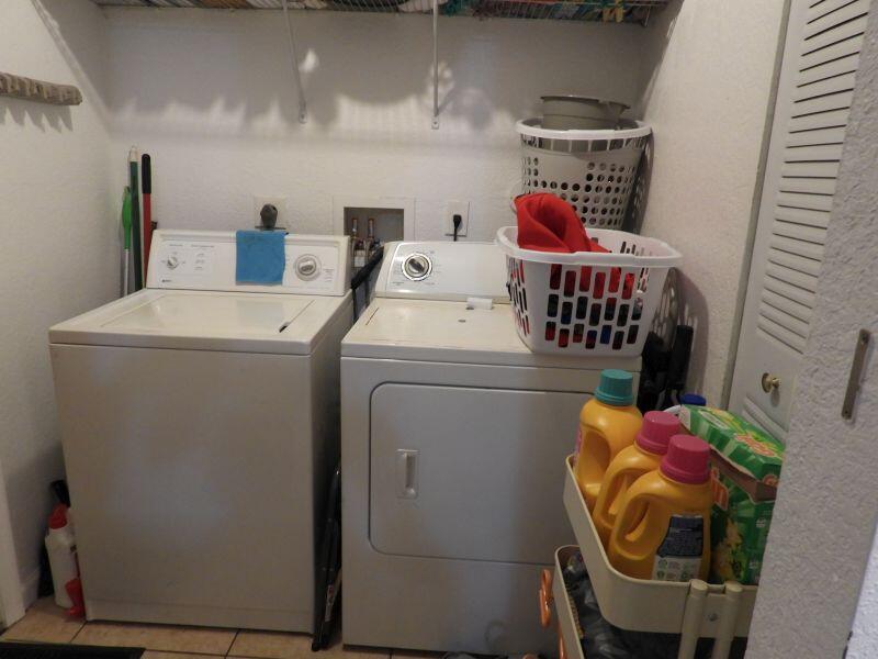 A laundry room features a white top-loading washer and dryer with laundry supplies nearby — 2764 NW 1st Court, Pompano Beach FL 33069, POMPANO BEACH, FL
