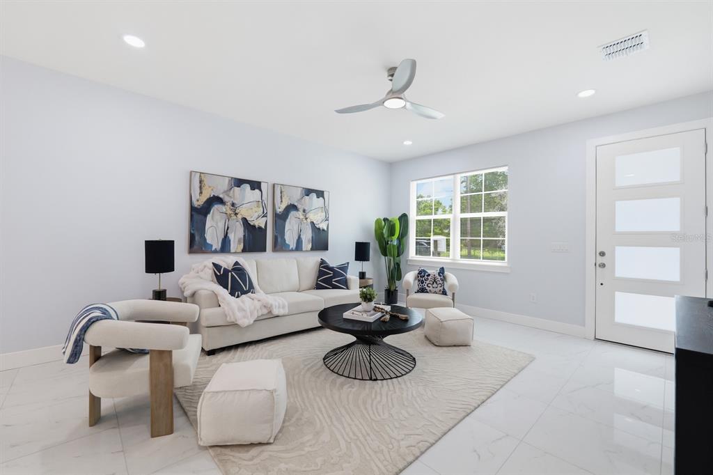 A bright living room features white tile floors, a modern ceiling fan, and neutral furniture — 8119 N DAKOTA AVENUE, TAMPA, FL