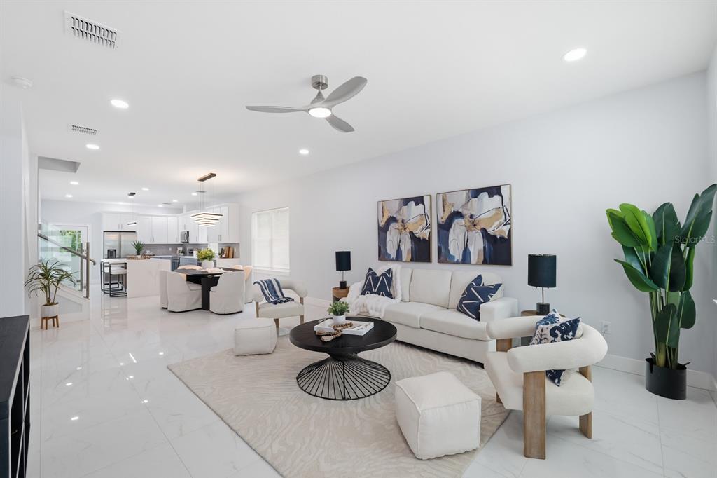 A bright, open-concept living room and dining area with white tile floors and modern furniture — 8119 N DAKOTA AVENUE, TAMPA, FL