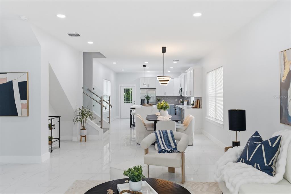 A bright open-concept living and dining area features white marble floors and modern kitchen cabinetry — 8119 N DAKOTA AVENUE, TAMPA, FL