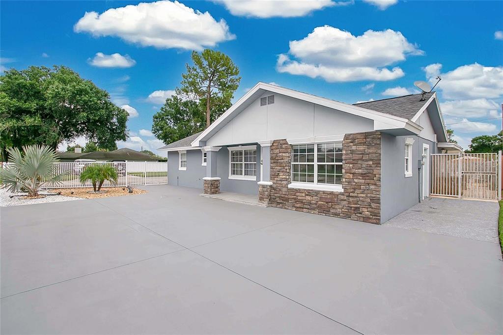 A single-story house with gray stucco walls, stone accents, and a large concrete driveway — 614 SIDNEY CIRCLE, WINTER HAVEN, FL