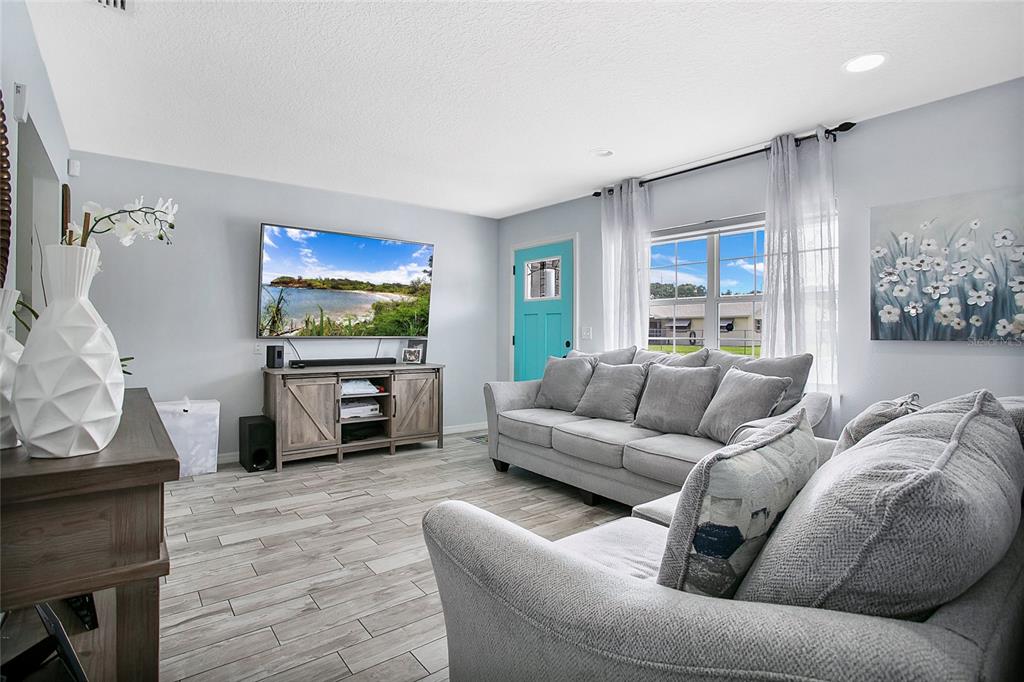 A living room features gray tile flooring, a gray sofa, and a bright blue front door — 614 SIDNEY CIRCLE, WINTER HAVEN, FL