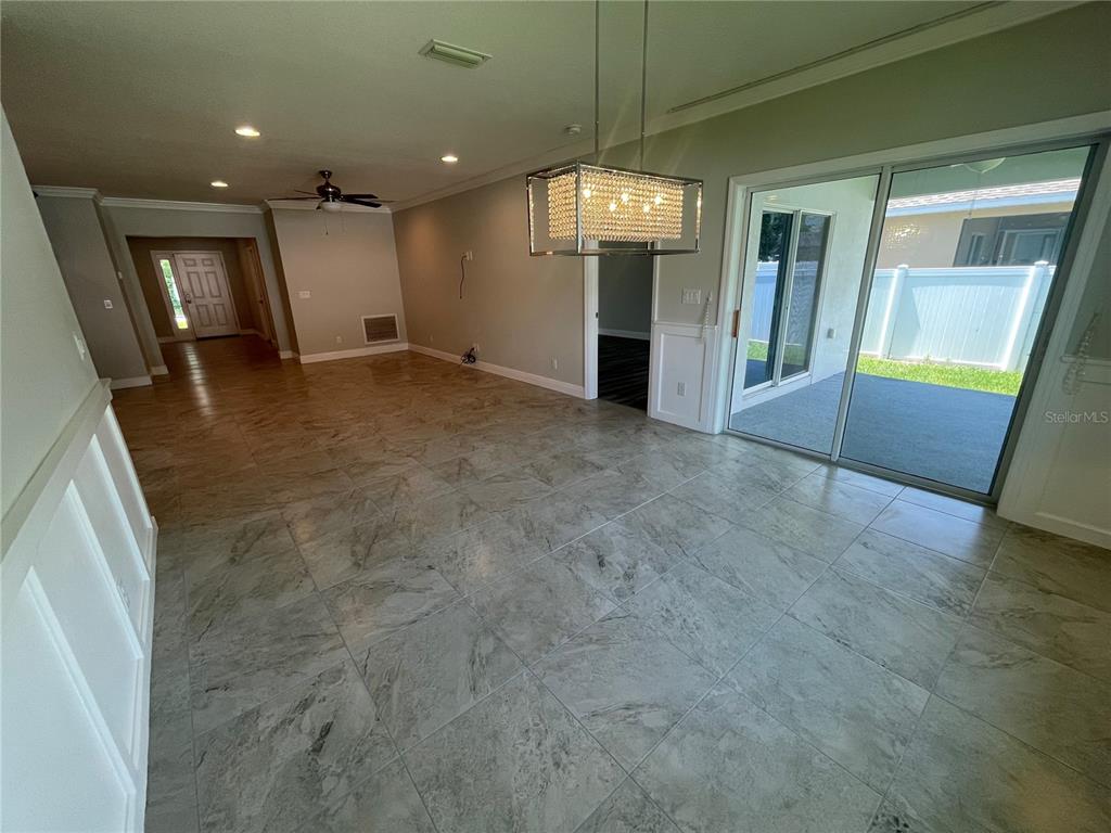 A dining area features large gray tile flooring, a crystal chandelier, and sliding glass patio doors — 232 CLAYTON STREET, BRANDON, FL