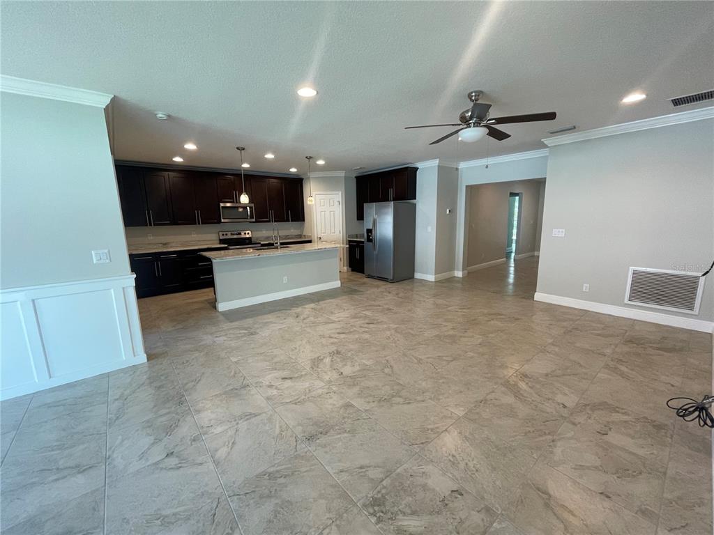 A kitchen with dark cabinets and a center island opens into a large tiled room — 232 CLAYTON STREET, BRANDON, FL