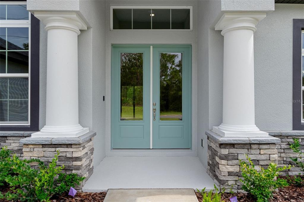 A light blue double front door is flanked by two white columns and stone bases — 60 CORKWOOD BOULEVARD, HOMOSASSA, FL