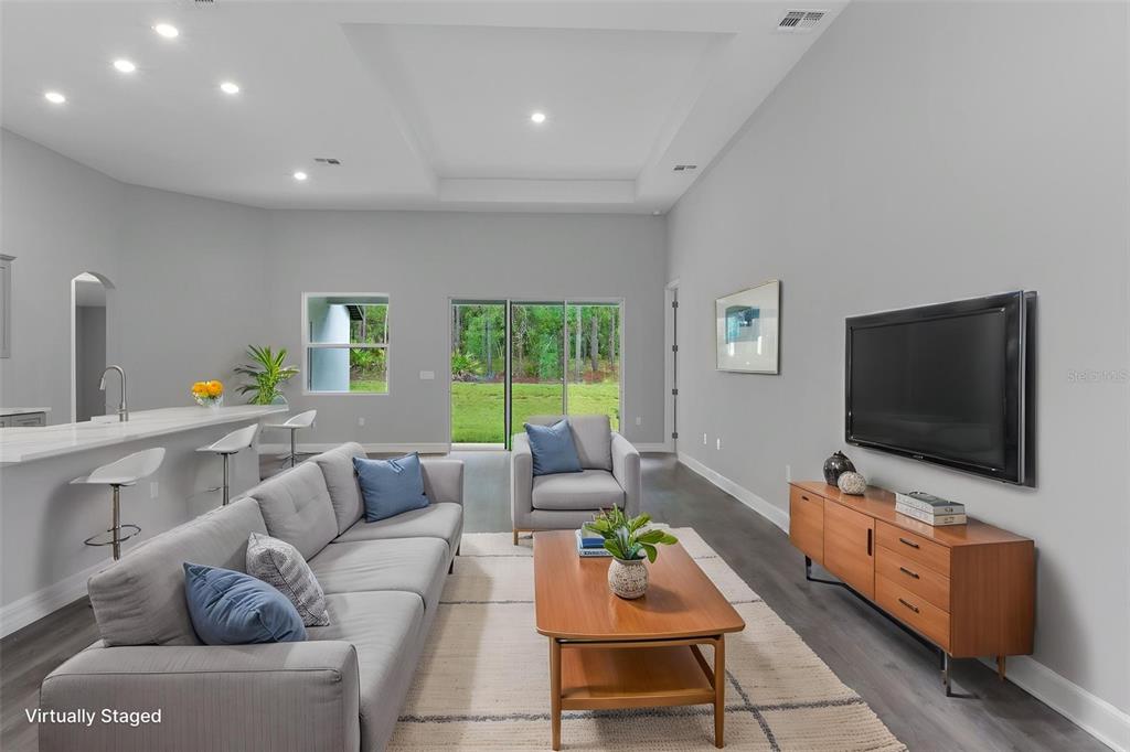 A living room with a grey sofa, wood coffee table, and television faces a sliding door — 60 CORKWOOD BOULEVARD, HOMOSASSA, FL