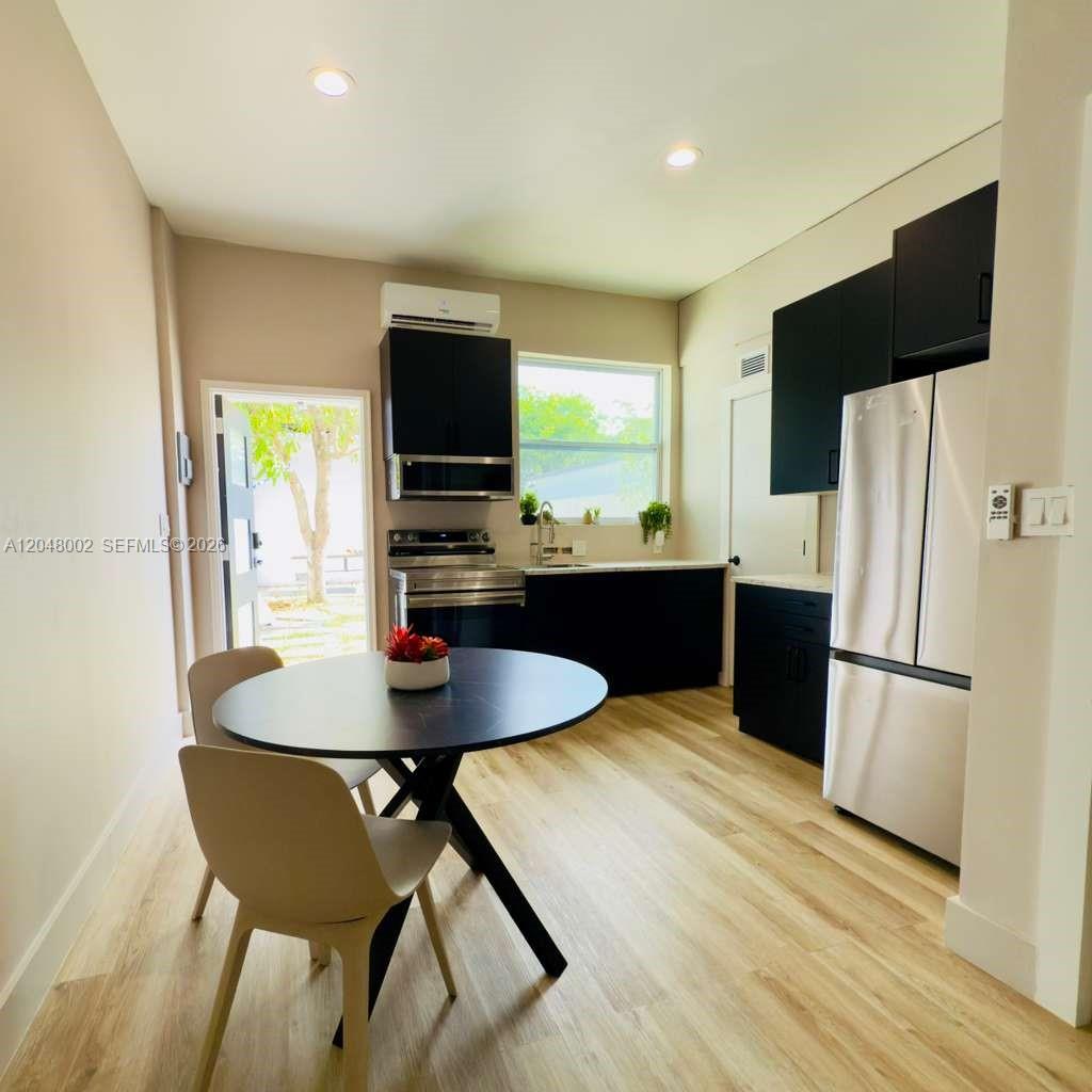 A kitchen features black cabinets, stainless steel appliances, a round dining table, and light flooring — 220 NW 126th St # B, North Miami FL 33168, NORTH MIAMI, FL