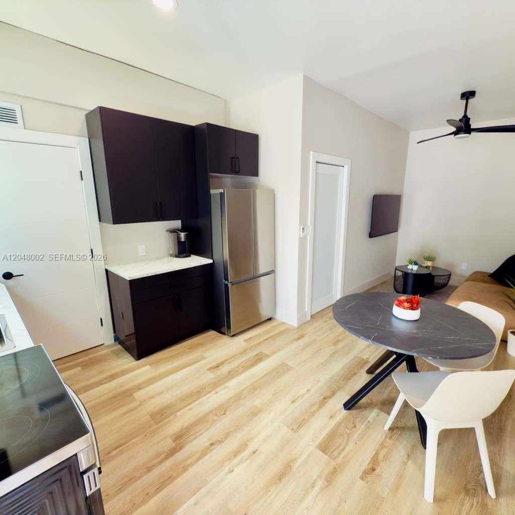 A kitchen with dark cabinets and stainless steel appliances opens into a dining area — 220 NW 126th St # B, North Miami FL 33168, NORTH MIAMI, FL