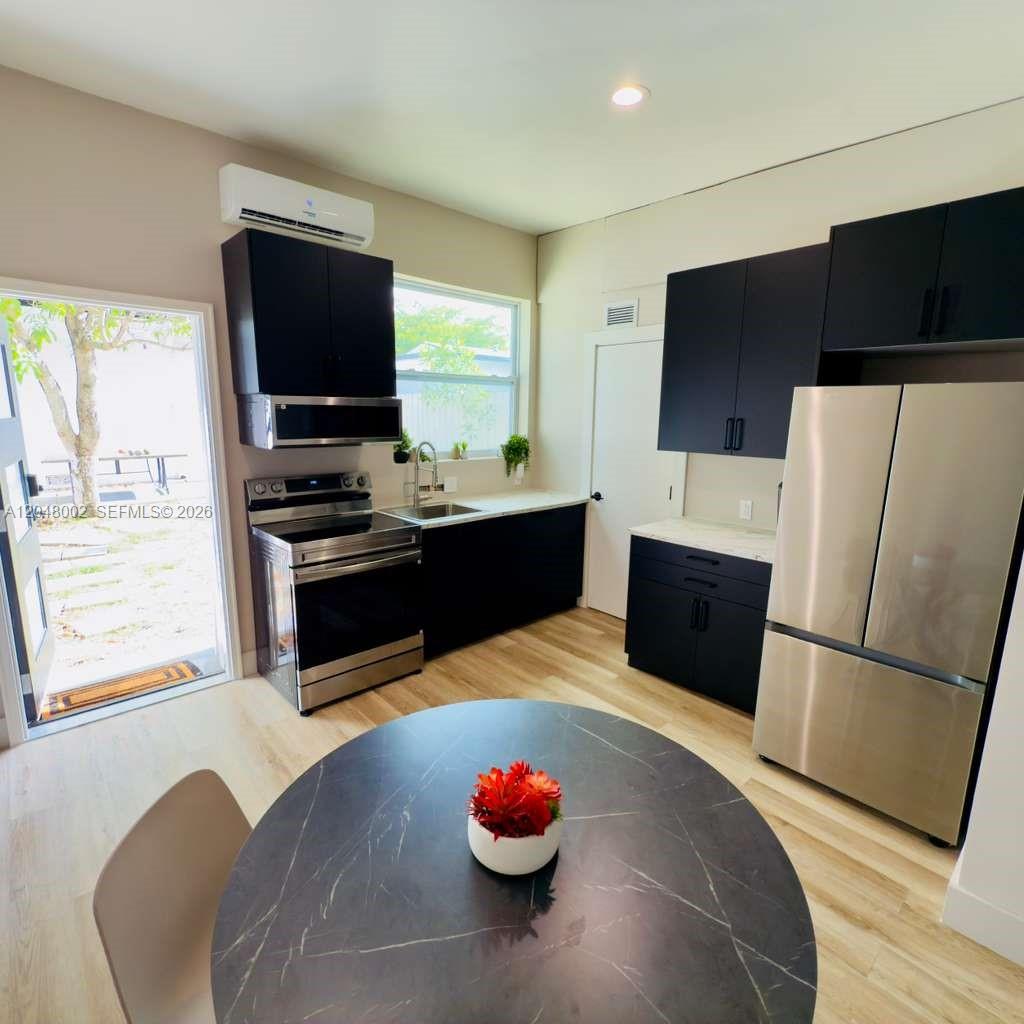 A modern kitchen features dark cabinetry, stainless steel appliances, and a round dining table — 220 NW 126th St # B, North Miami FL 33168, NORTH MIAMI, FL