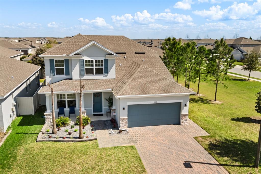 A two-story house exterior at night features blue LED roofline lighting and a paved driveway — 660 BIG PINE AVENUE, MINNEOLA, FL