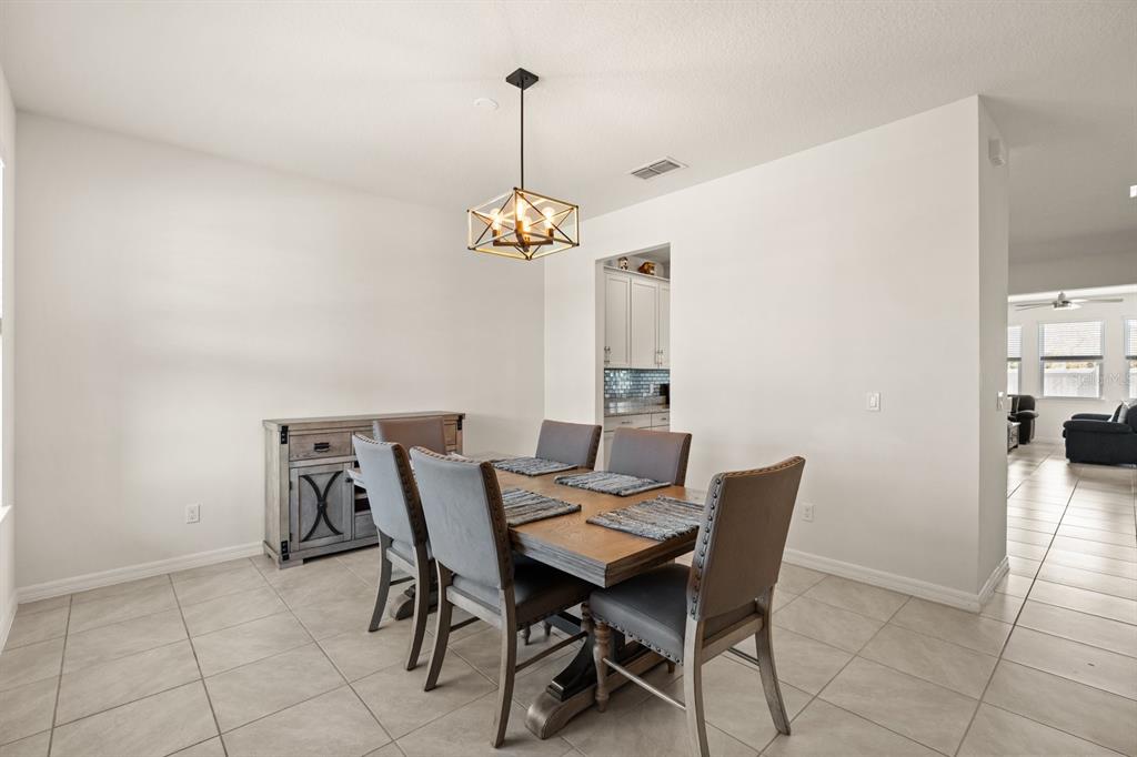 A dining room features a wooden table with six gray chairs and a pendant light — 660 BIG PINE AVENUE, MINNEOLA, FL