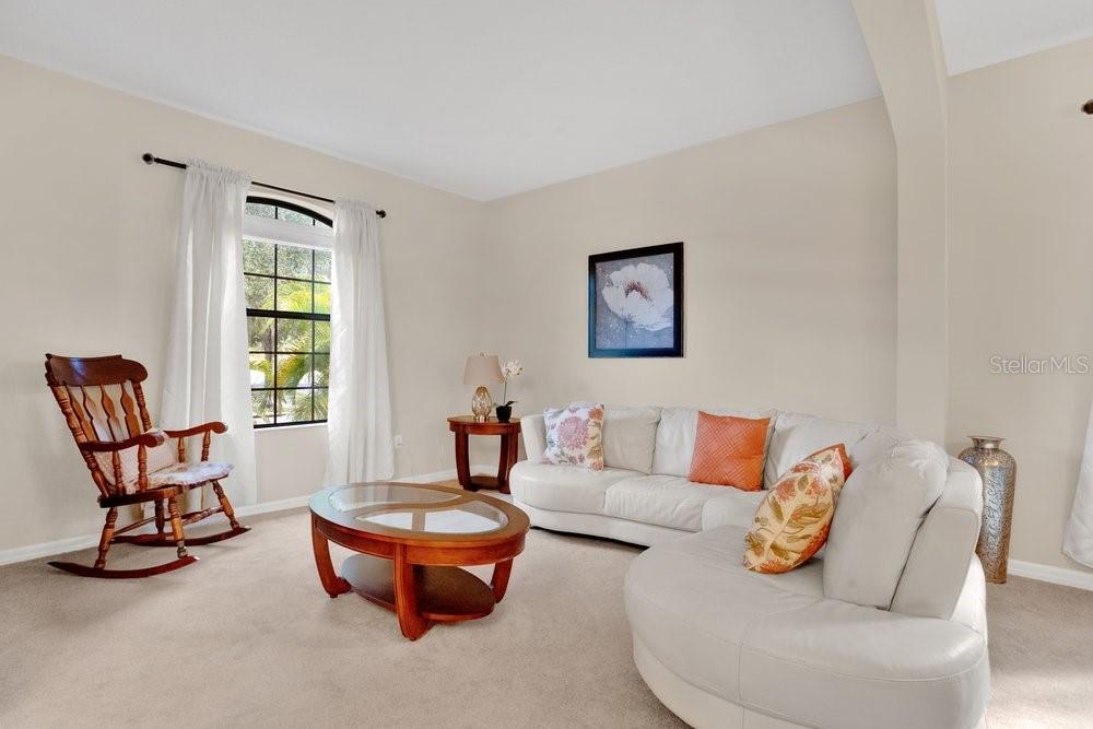 A living room features a white sectional sofa, a wooden rocking chair, and a coffee table — 19402 SWEET GRASS WAY, LUTZ, FL