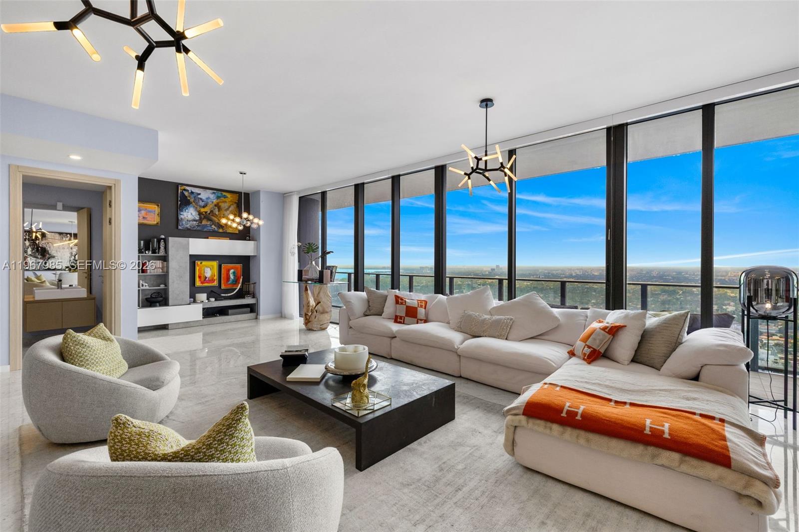 A modern living room features a large sectional sofa, floor-to-ceiling windows, and marble flooring — 1000 Brickell Plz, Miami FL 33131, MIAMI, FL