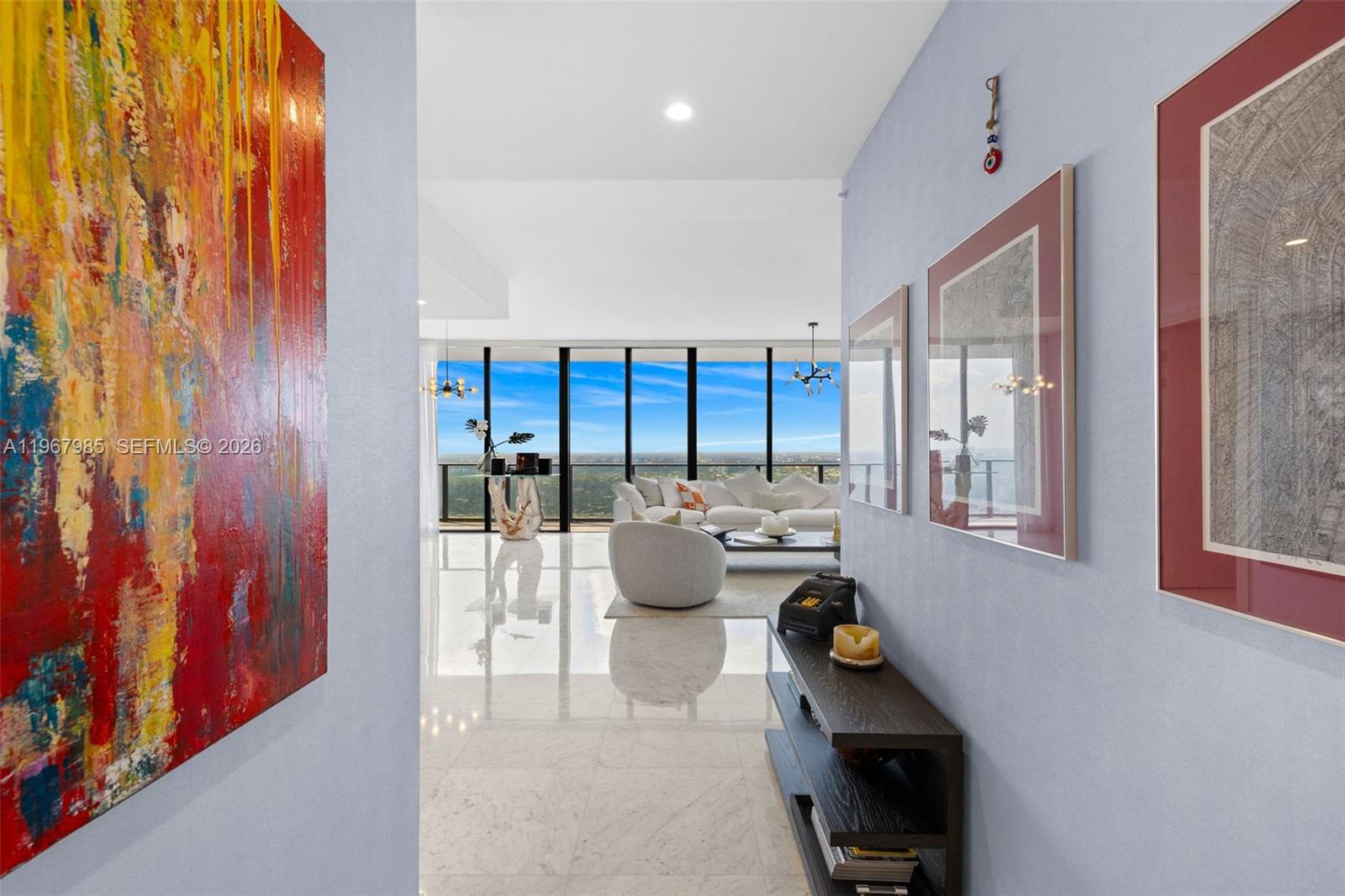 A hallway with artwork and a console table leads into a bright, open-concept living area — 1000 Brickell Plz, Miami FL 33131, MIAMI, FL