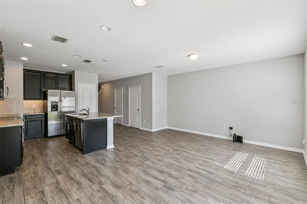 A kitchen with dark cabinets and a granite island opens into a spacious living area — 1283 FLOWING TIDE DRIVE, ORLANDO, FL