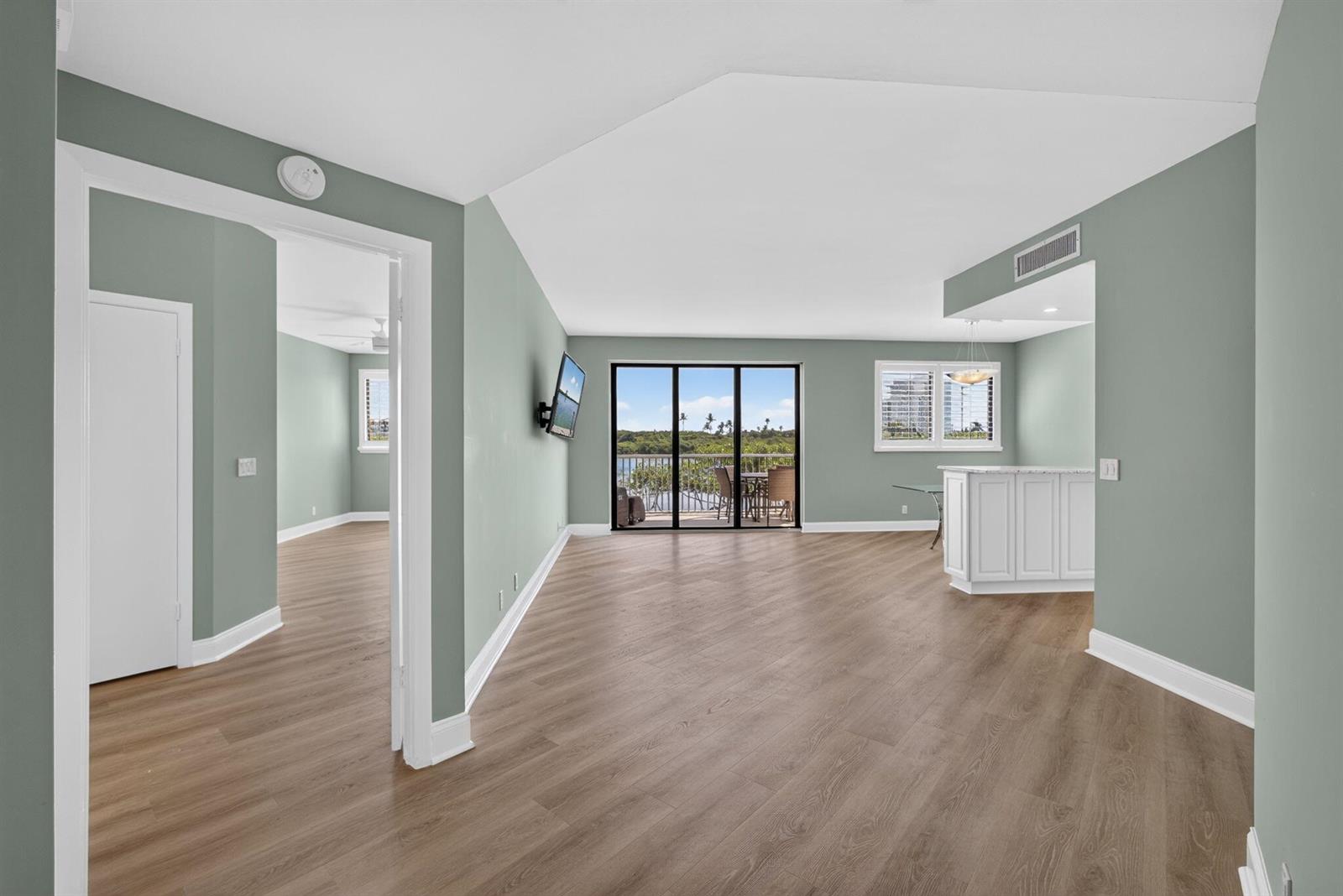 An open-concept living area features light green walls, wood-look flooring, and a balcony view — 200 Waterway Road # 206, Tequesta FL 33469, TEQUESTA, FL