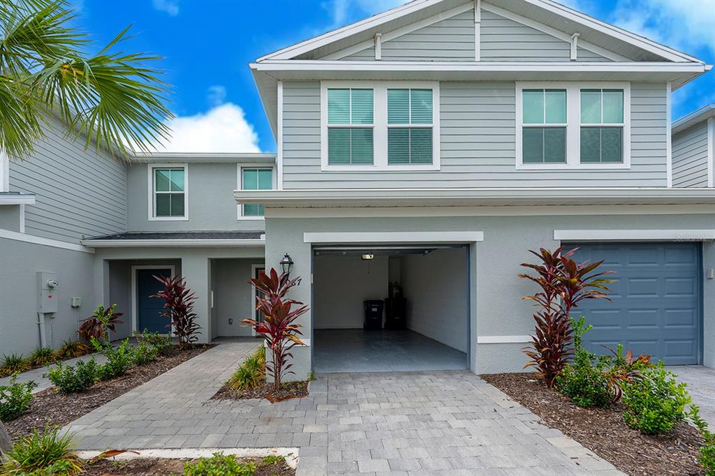 A two-story townhouse exterior features a paved driveway, an open garage, and a front entrance — 14087 LILAC SKY TERRACE, LAKEWOOD RANCH, FL